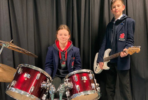 2 students playing drums and guitar